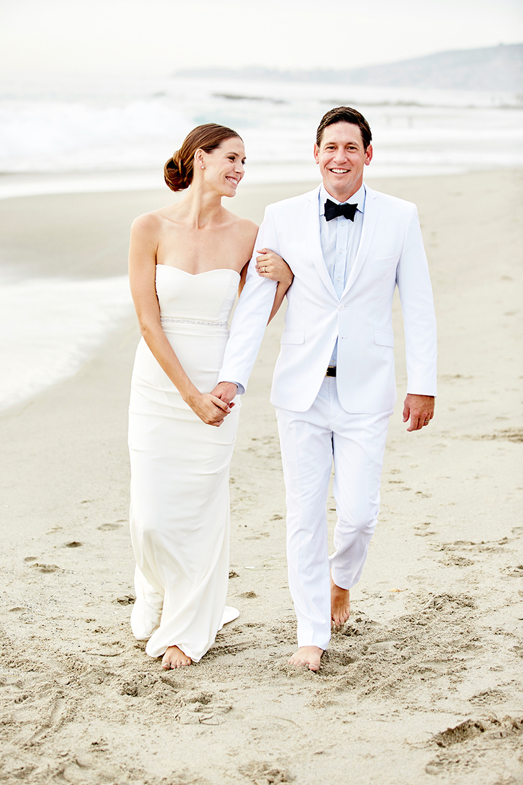 Bride and groom walk on Beach after ceremony ion Laguna Beach,  California